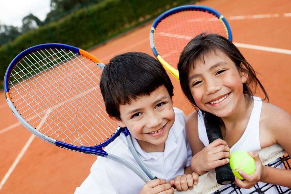 Portrait of young tennis players smiling at the court