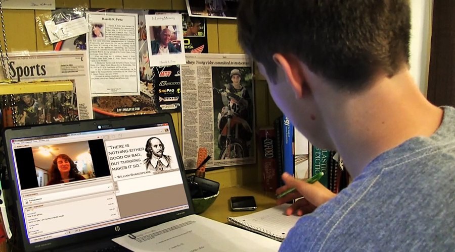 Male student learning history at virtual school on laptop